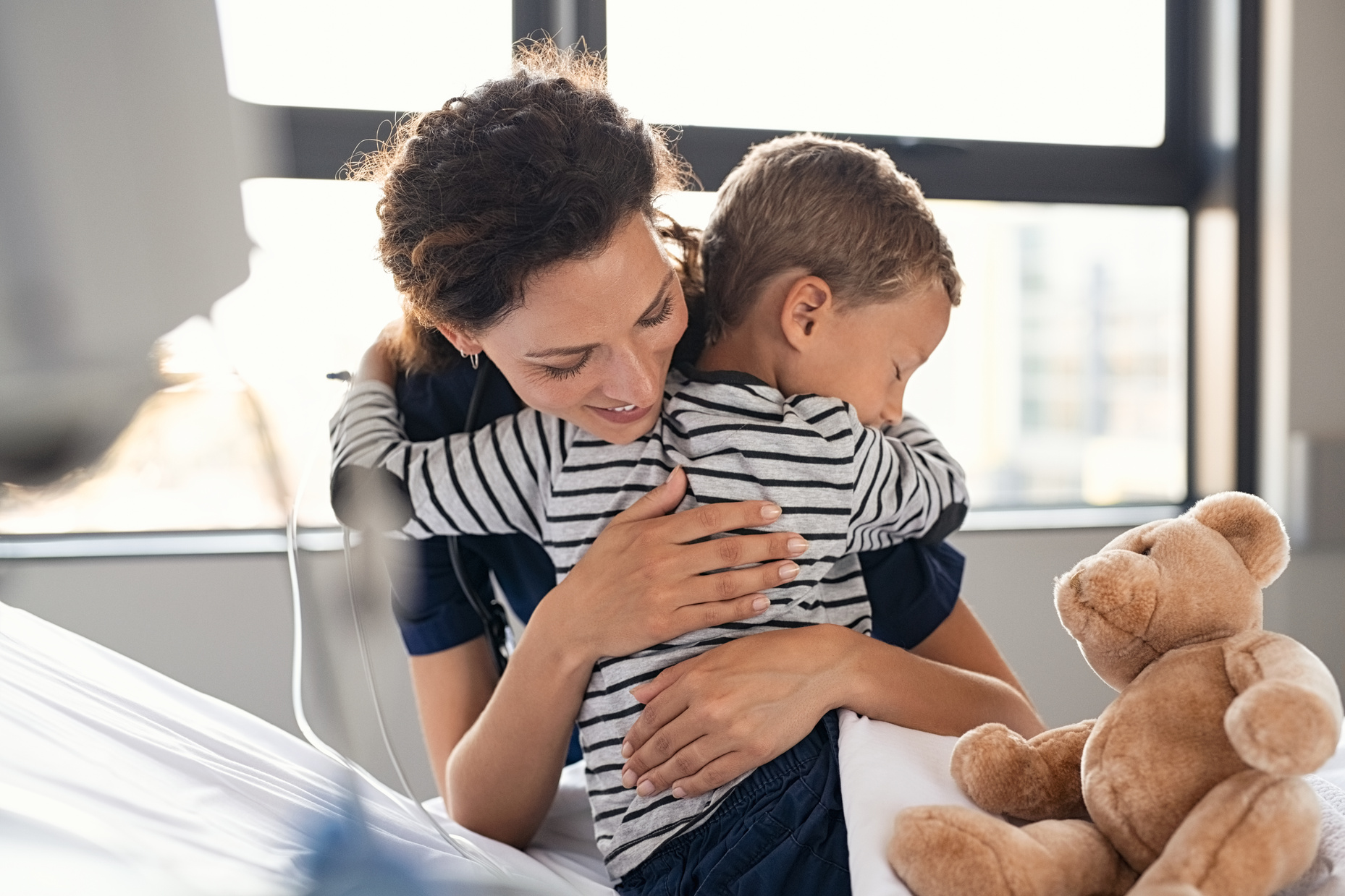 Cute Child Hugging Nurse at Hospital