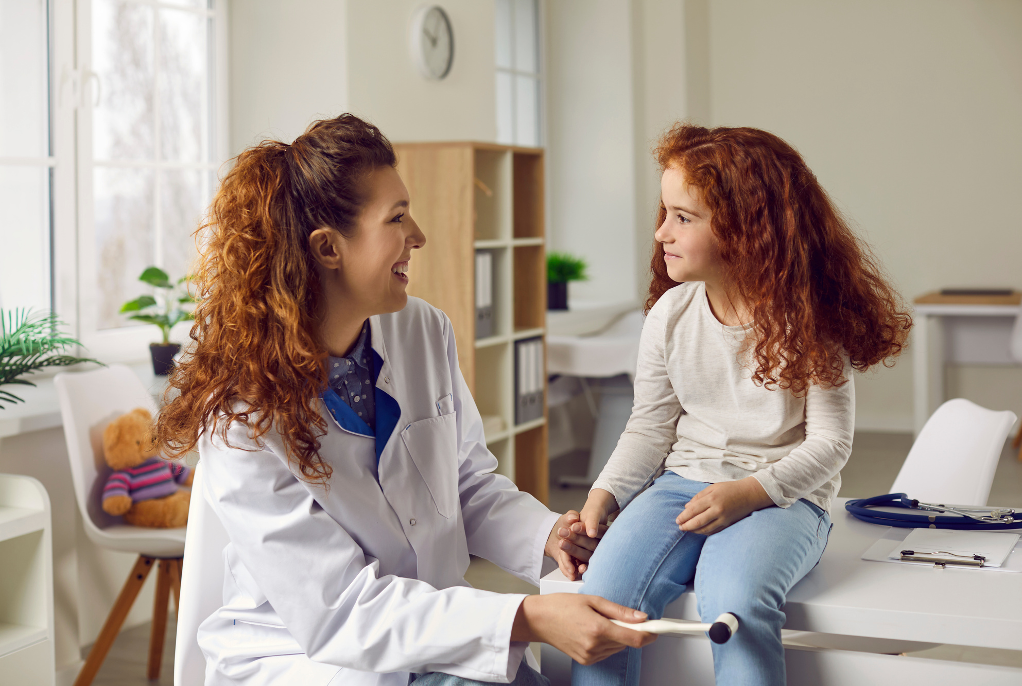 Female Doctor Taps Little Girl on Knee with Special Hammer to Check Her Reflexes.